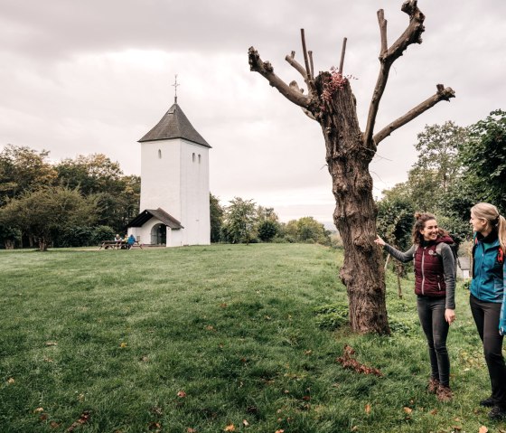 Zwei Frauen stehen auf einer Wiese vor dem Swister Turm. Der Himmel ist bewölkt, und im Hintergrund sind Bäume zu sehen., © Paul Meixner Zwei Frauen stehen auf einer Wiese vor dem Swister Turm. Der Himmel ist bewölkt, und im Hintergrund sind Bäume zu sehen., © Paul Meixner