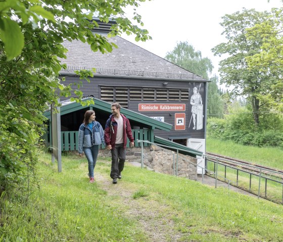 Ein Paar spaziert vor der Römischen Kalkbrennerei Iversheim durch eine grüne Landschaft., © Eifel Tourismus GmbH, AR-shapefruit AG Ein Paar spaziert vor der Römischen Kalkbrennerei Iversheim durch eine grüne Landschaft., © Eifel Tourismus GmbH, AR-shapefruit AG