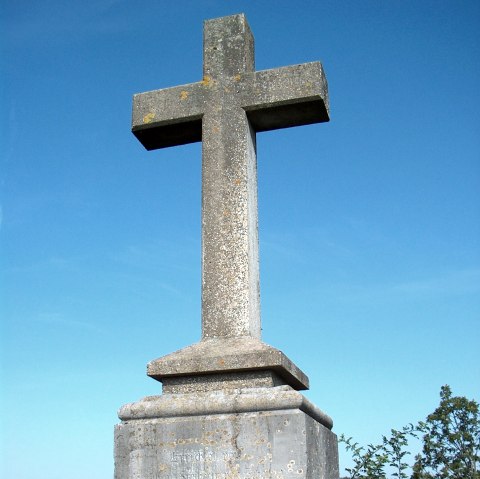 A stone cross on a pedestal stands in front of a clear blue sky. Trees and a hill can be seen in the background., © Rursee-Touristik GmbH A stone cross on a pedestal stands in front of a clear blue sky. Trees and a hill can be seen in the background., © Rursee-Touristik GmbH