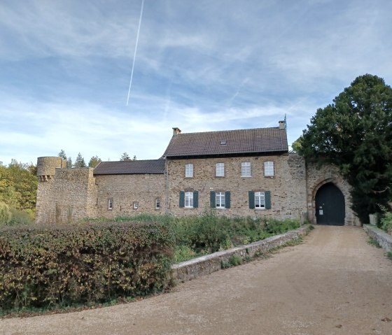 Die Hardtburg mit steinernen Mauern und Torbogen, umgeben von Bäumen und blauem Himmel. Ein Weg führt zur Burg., © Sweco GmbH Die Hardtburg mit steinernen Mauern und Torbogen, umgeben von Bäumen und blauem Himmel. Ein Weg führt zur Burg., © Sweco GmbH