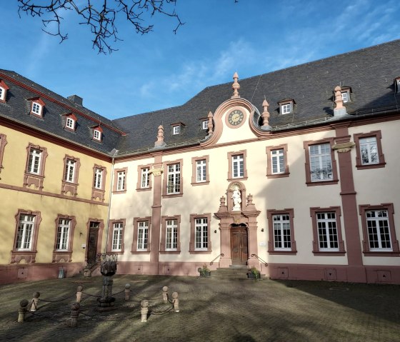 Barocke Fassade des Klosters Steinfeld mit Uhr und Statue im Innenhof, umgeben von blauem Himmel und Bäumen., © Sweco GmbH