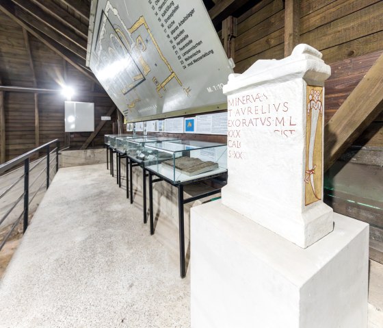 Innenansicht einer römischen Kalkbrennerei mit Vitrinen, Informationstafeln und einer Stele mit lateinischer Inschrift., © Eifel Tourismus GmbH AR-shapefruit AG
