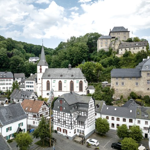 Luftaufnahme von Blankenheim: Fachwerkh&auml;user, eine Kirche und eine Burg auf einem H&uuml;gel, umgeben von gr&uuml;nen B&auml;umen., &copy; Eifel Tourismus GmbH, Dennis Stratmann