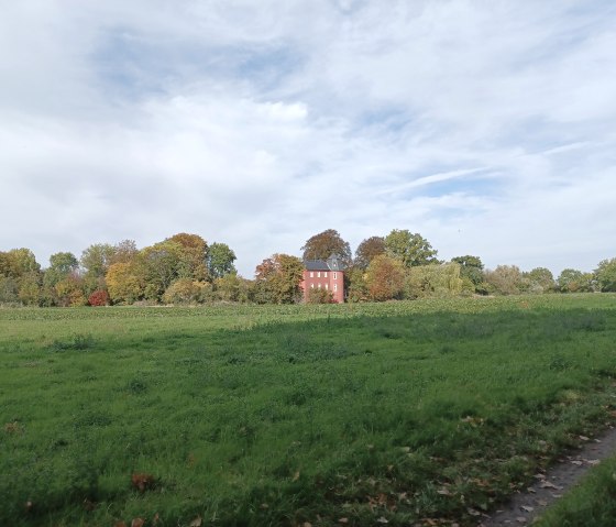 Burg Kessenich steht hinter einer gr&uuml;nen Wiese, umgeben von herbstlich gef&auml;rbten B&auml;umen unter einem bew&ouml;lkten Himmel., &copy; Sweco GmbH