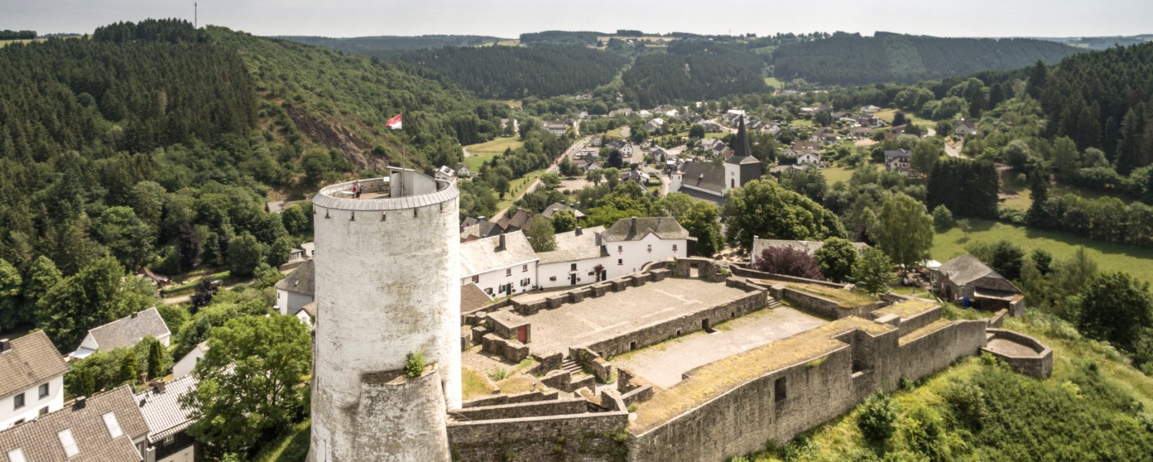 Luftaufnahme der Burg Reifferscheid mit rundem Turm, umgeben von gr&uuml;ner Landschaft und Dorf im Hintergrund., &copy; Eifel Tourismus GmbH, D. Ketz